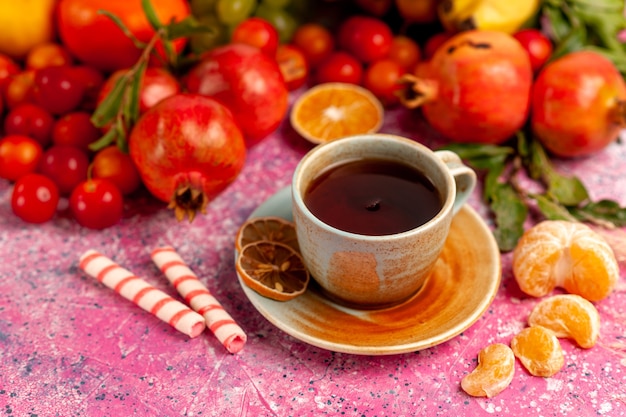 Vorderansicht frische Fruchtzusammensetzung mit Tasse Tee auf der hellrosa Oberfläche