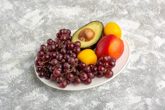Vorderansicht frische Früchte Trauben Pfirsich und Avocado Innenplatte auf weißer Oberfläche