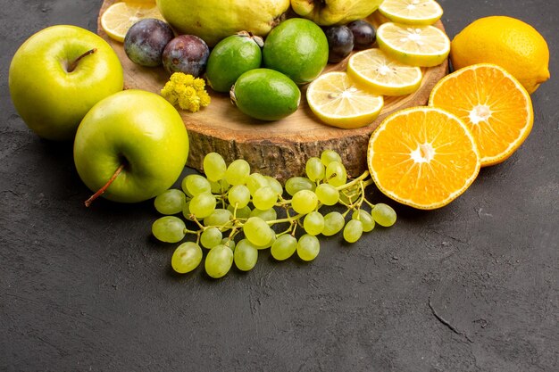 Vorderansicht frische früchte trauben zitronenscheiben pflaumen und quitten auf dunklem hintergrund reife frische früchte pflanzenbaum