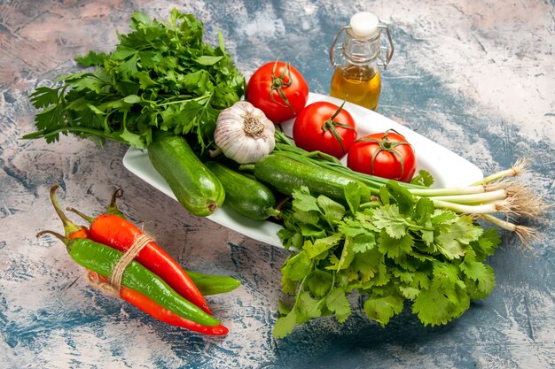 Vorderansicht frische Frühlingszwiebeln mit Tomaten und Grüns auf hellblauem Hintergrund Farbfoto reife Mahlzeit Salat