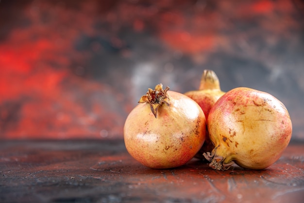 Vorderansicht frische Granatäpfel auf dunkelrot mit Kopierraum