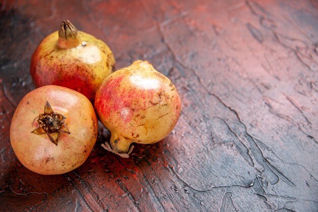 Vorderansicht frische Granatäpfel auf dunkelrotem Holzboden mit Kopierraum