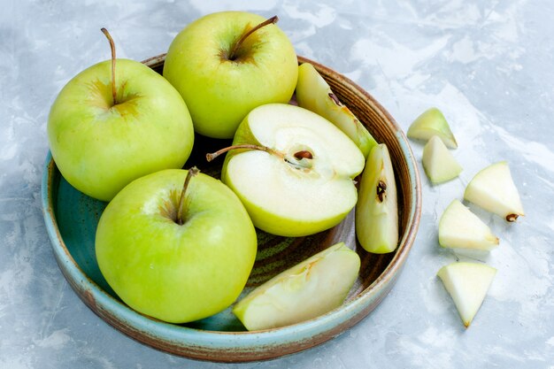 Vorderansicht frische grüne Äpfel in Scheiben geschnitten und ganze Früchte auf hellweißem Oberflächenfrucht frisches weiches reifes Vitamin