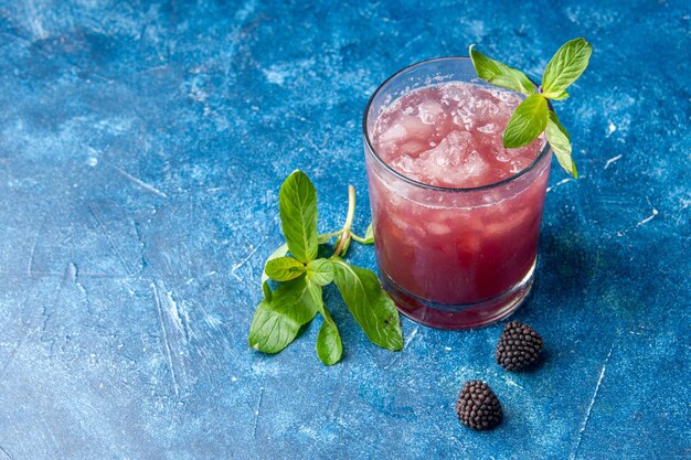 Vorderansicht frische kühle Limonade in kleinem Glas mit Eis auf blauem Hintergrund Saftgetränk Farbe Wasser Fruchtcocktail