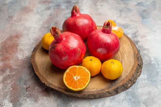 Vorderansicht frische Mandarinen mit roten Granatäpfeln auf hellem Hintergrund Foto exotischer Saft Vitamin Geschmack Obstbaum Farbe