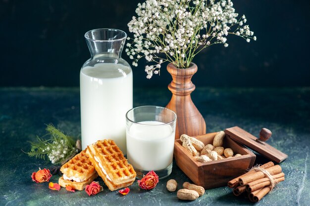 Vorderansicht frische Milch mit süßen kleinen Kuchen auf dunkelblauem Dessert Honigkuchen Frühstück süßer Milchmorgen