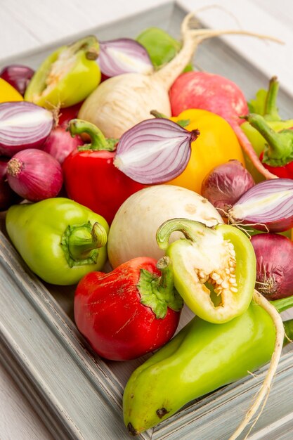 Vorderansicht frische Paprika mit Rettich und Zwiebeln auf dem weißen Gemüsepfefferfarbe reifen Salat gesundes Leben Mahlzeit Foto