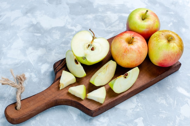 Vorderansicht frische Äpfel in Scheiben geschnitten und ganze Früchte auf hellweißer Oberfläche Frucht frisch ausgereiftes reifes Vitamin