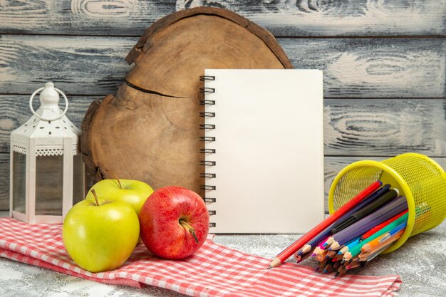 Vorderansicht frische Äpfel mit bunten Bleistiften auf grauem Hintergrund reife weiche frische Früchte