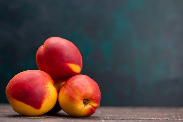 Vorderansicht frische Pfirsiche köstliche süße Früchte auf dunkelblauer Oberfläche Fruchtsaft milder frischer Sommer
