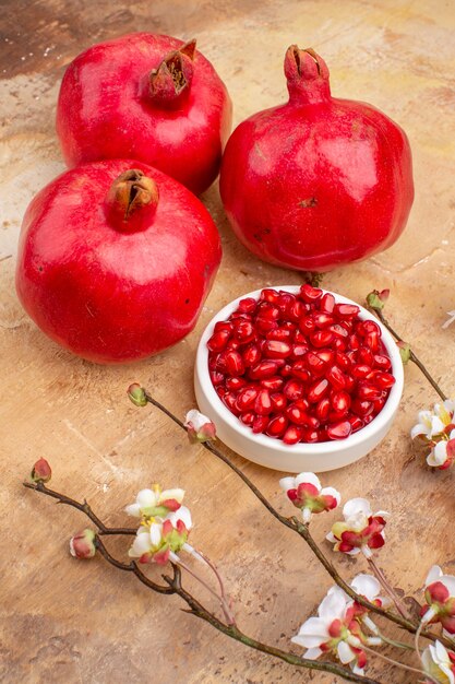 Vorderansicht frische rote Granatäpfel geschält und mit ganzen Früchten auf braunem Hintergrund Farbe Fruchtfoto milder Saft