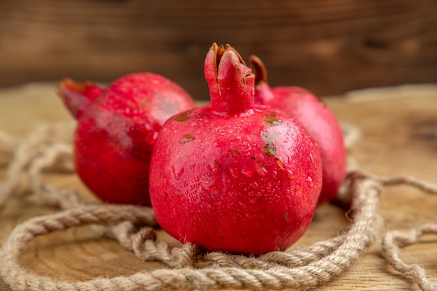 Vorderansicht frische rote Granatäpfel mit Seilen auf dem Holztisch Farbe Fruchtsaft Fotobaum