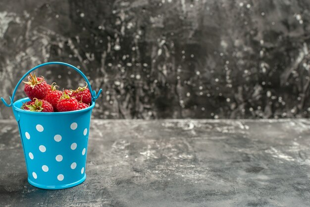 Vorderansicht frische rote himbeeren in einem kleinen korb auf grauer fruchtfarbe preiselbeere wilde fotobeere freier platz für text