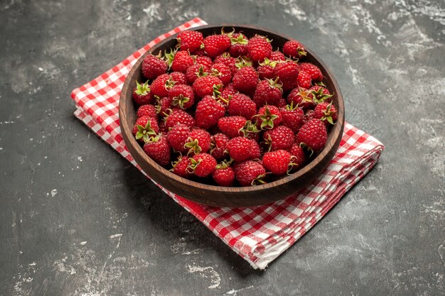 Vorderansicht frische rote Himbeeren innerhalb des Tellers auf grauem Fruchtbeerenfarbpreiselbeerwildfoto