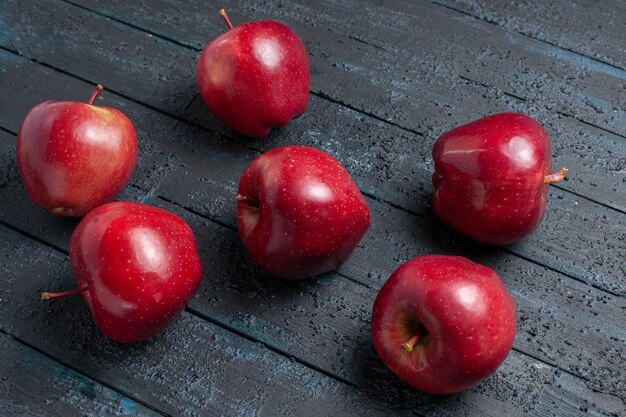 Vorderansicht frische rote Äpfel ausgereifte und reife Früchte auf dunkelblauem Schreibtisch Fruchtfarbe rotes Pflanzenvitamin frisch