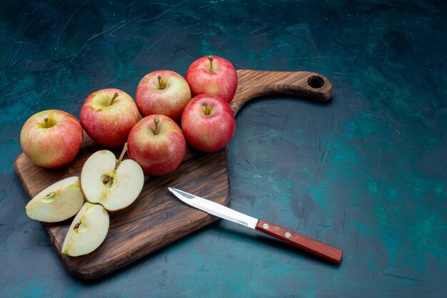 Vorderansicht frische rote Äpfel saftig und weich mit braunem Schreibtisch auf dem dunkelblauen Hintergrundfrucht frisches reifes mildes Vitamin