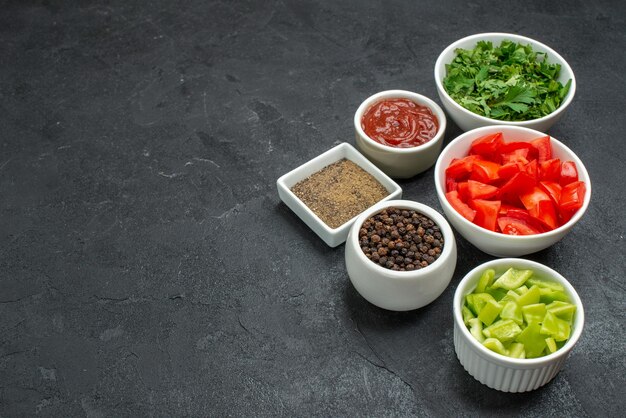 Vorderansicht frische rote Tomaten geschnittenes Gemüse mit Grüns auf dunklem Schreibtisch reife Salatgesundheitsmahlzeit