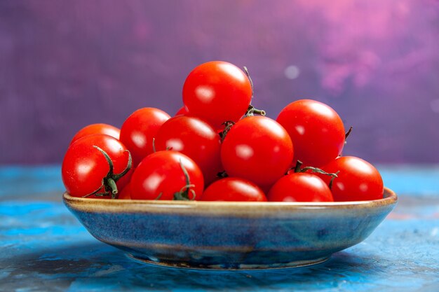 Vorderansicht frische rote Tomaten im Teller auf blauem Tischfoto Essen Gemüsesalat Farbe