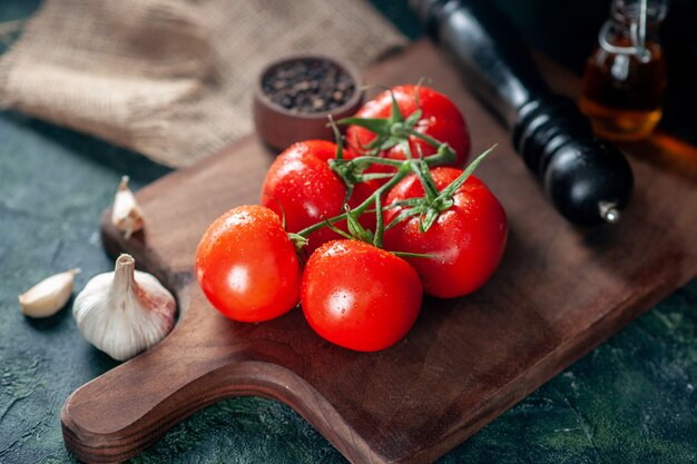 Vorderansicht frische rote Tomaten mit Knoblauch auf dunklem Hintergrund