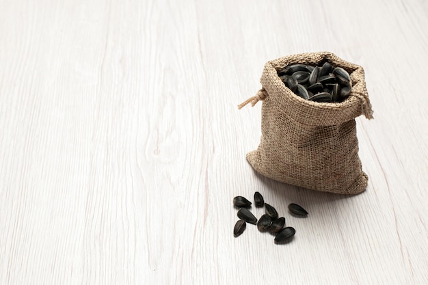 Vorderansicht frische Sonnenblumenkerne schwarz gefärbte Samen in kleiner Tasche auf weißem Hintergrund Samen-Snack-Foto viele Öle