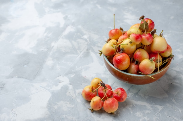 Vorderansicht frische Süßkirschen im Topf auf dem hellen Schreibtischfrucht frische milde saftige Farbe