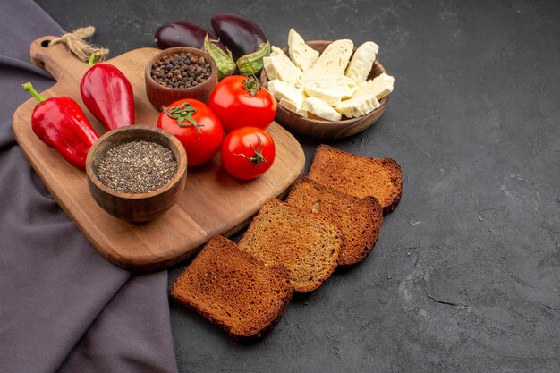 Vorderansicht frische Tomaten mit dunklen Brotlaiben und Weißkäse auf dunklem Raum