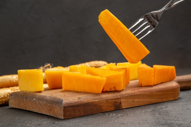 Vorderansicht frischer geschnittener Käse mit Brötchen auf dem dunklen Snackmahlzeitfarbfotofrühstück knusprig