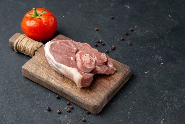 Vorderansicht Frischfleischscheibe rohes Fleisch mit Tomate auf dunklem Hintergrund Grillgericht Pfeffer Küche Essen Kuh Essen Salat Tiermehl