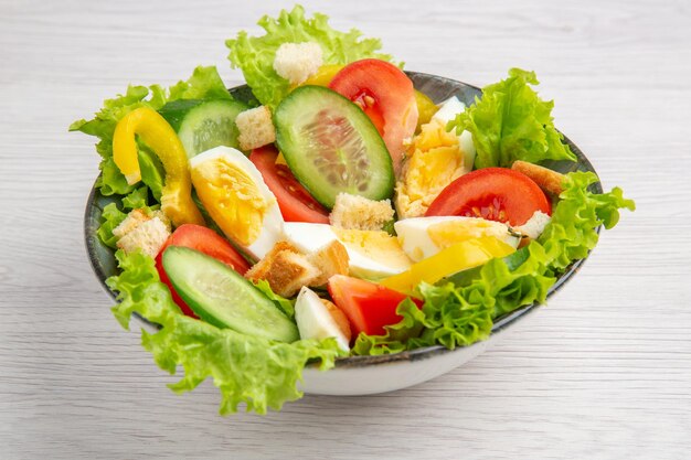 Vorderansicht Frischgemüsesalat mit Eiern auf weißem Hintergrund reifes Essen Frühstück Salat Mahlzeit Mittagessen Farbe