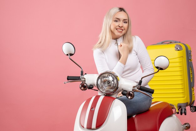 Vorderansicht froh junge Dame auf Moped mit gelbem Koffer