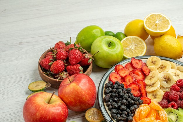 Vorderansicht-Fruchtzusammensetzung mit geschnittenem Obstsalat auf weißer Oberfläche exotischer fruchtiger Beerenreifes ausgereiftes Foto