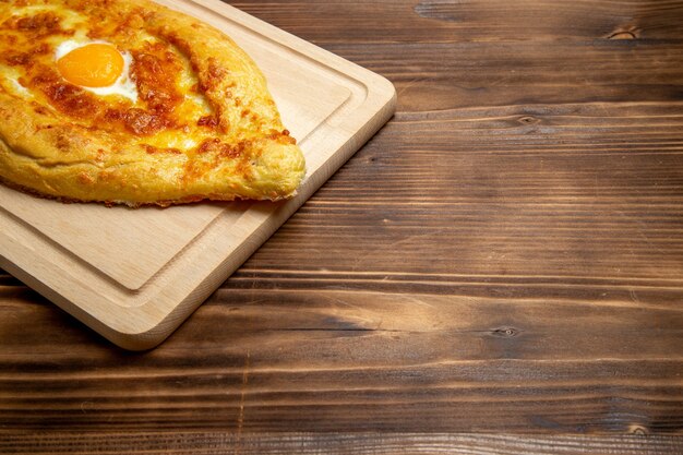 Vorderansicht gebackenes Brot mit gekochtem Ei auf hölzernem Schreibtischbrotbrötchenlebensmittelei-Frühstücksteig