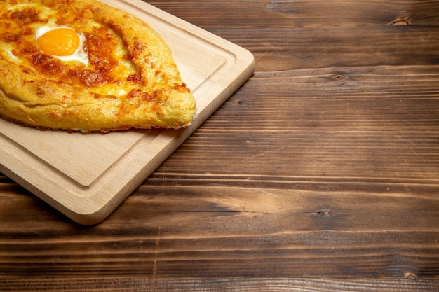 Vorderansicht gebackenes Brot mit gekochtem Ei auf hölzernem Schreibtischbrotbrötchenlebensmittelei-Frühstücksteig