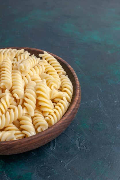 Vorderansicht geformte italienische Pasta köstlich aussehende kleine Pasta innerhalb des braunen Topfes auf dunkelblauem Schreibtisch