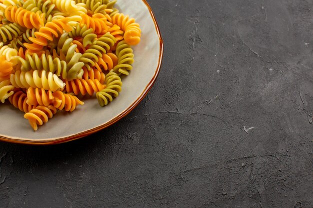 Vorderansicht gekochte italienische Pasta ungewöhnliche Spiralnudeln im Teller auf dunklem Schreibtisch Pasta-Mahlzeit, die Gericht Abendessen kocht