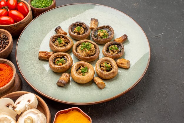 Vorderansicht gekochte Pilze mit Tomaten und Gewürzen auf einem dunklen Hintergrundgericht Mahlzeit Kochen von Pilzen Abendessen