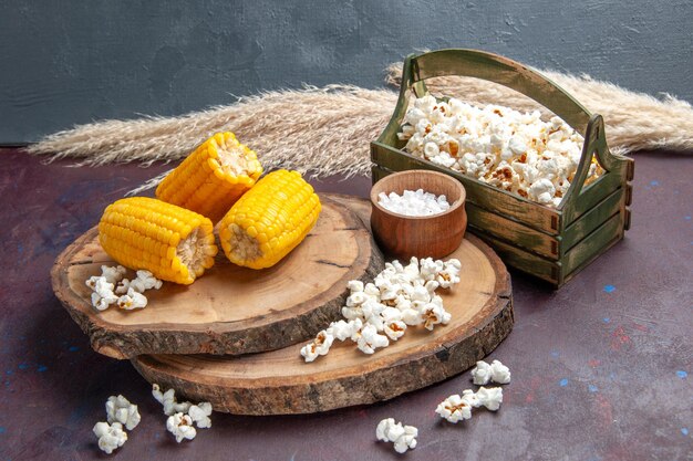 Vorderansicht gelbe Hühneraugen geschnitten mit Popcorn auf der dunklen Oberfläche Mais-Snack-Pflanzen-Baumöl