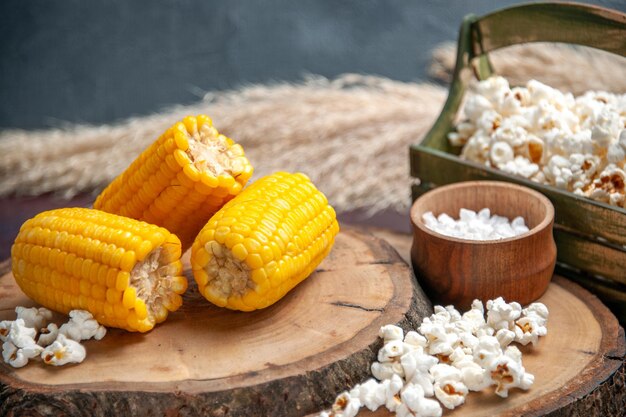 Vorderansicht gelbe Hühneraugen geschnitten mit Popcorn auf der dunklen Oberfläche Mais-Snack-Pflanzen-Baumöl