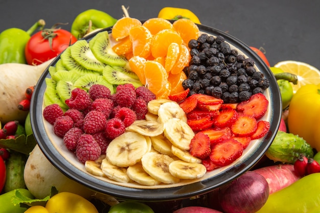 Vorderansicht Gemüsezusammensetzung frisches Gemüse mit geschnittenen Früchten auf dunkler, gesunder Lebenspflanze, reife Ernährung, Salatfarbe