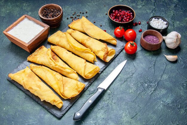 Vorderansicht gerollte Pfannkuchen mit Tomaten auf dunkler Oberfläche ausgekleidet