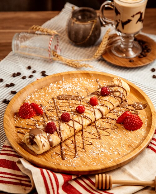 Vorderansicht gerollter Pfannkuchen mit Schokoladenglasur und Erdbeeren