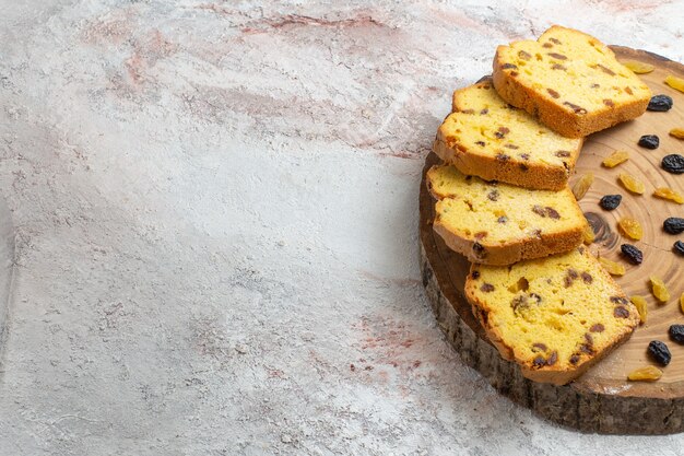 Vorderansicht geschnittener Rosinenkuchen mit frischen Rosinen auf dem hellweißen Schreibtisch