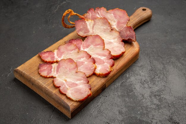 Vorderansicht geschnittener Schinken auf Holzschreibtisch und die graue Fotofarbe Fleischessen Mahlzeit rohes Schwein