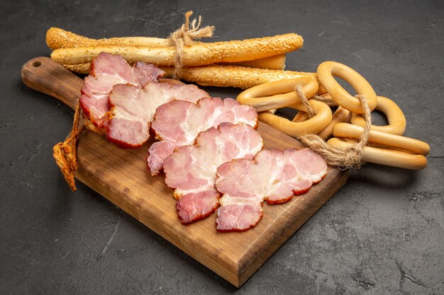 Vorderansicht geschnittener Schinken mit süßen Crackern und Brötchen auf grauer Fotofleischnahrung roher Schweinfarbe