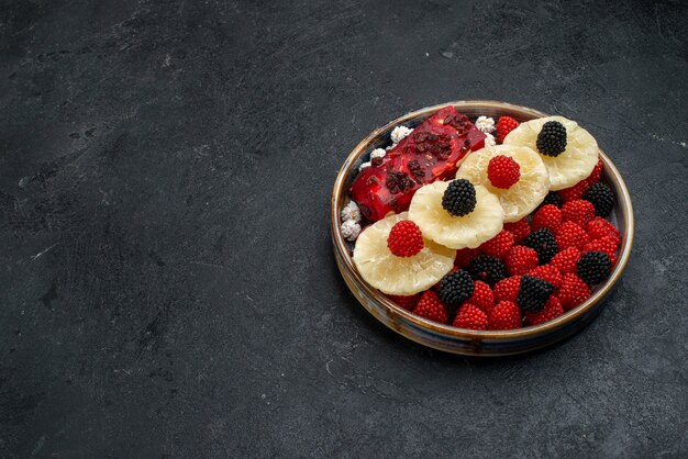 Vorderansicht getrocknete Ananasringe mit Confiture Beeren auf dunkelgrauen Oberflächenfrüchten trockene Rosinen süße Zuckersüßigkeiten