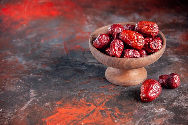 Vorderansicht getrocknete rote Jujubes auf dunkelrotem Hintergrundfruchturlaub horizontal sauer trocken