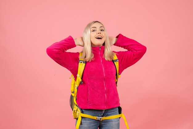 Vorderansicht glückliche reisende Frau in der Freizeitkleidung, die auf rosa Wand steht