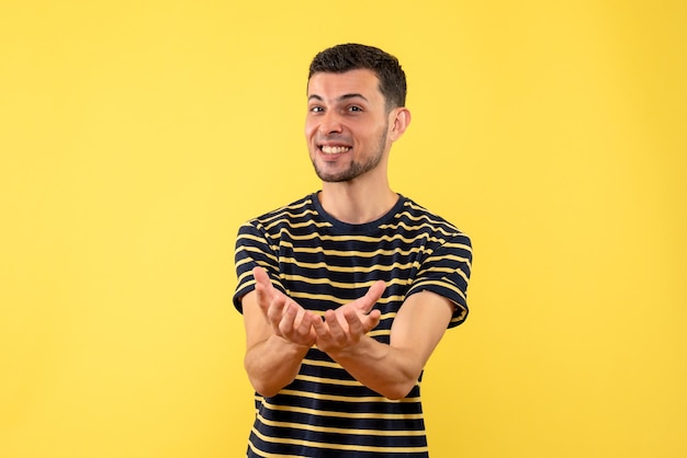 Vorderansicht glücklicher junger Mann im schwarzen und weißen gestreiften T-Shirt gelben isolierten Hintergrund