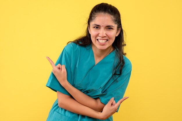 Vorderansicht glücklicher weiblicher Arzt, der auf gelbem Hintergrund steht