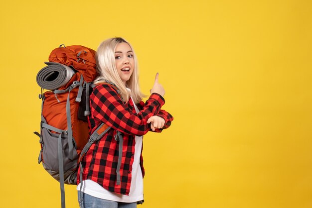 Vorderansicht glückliches blondes Mädchen mit ihrem Rucksack, der nach hinten zeigt